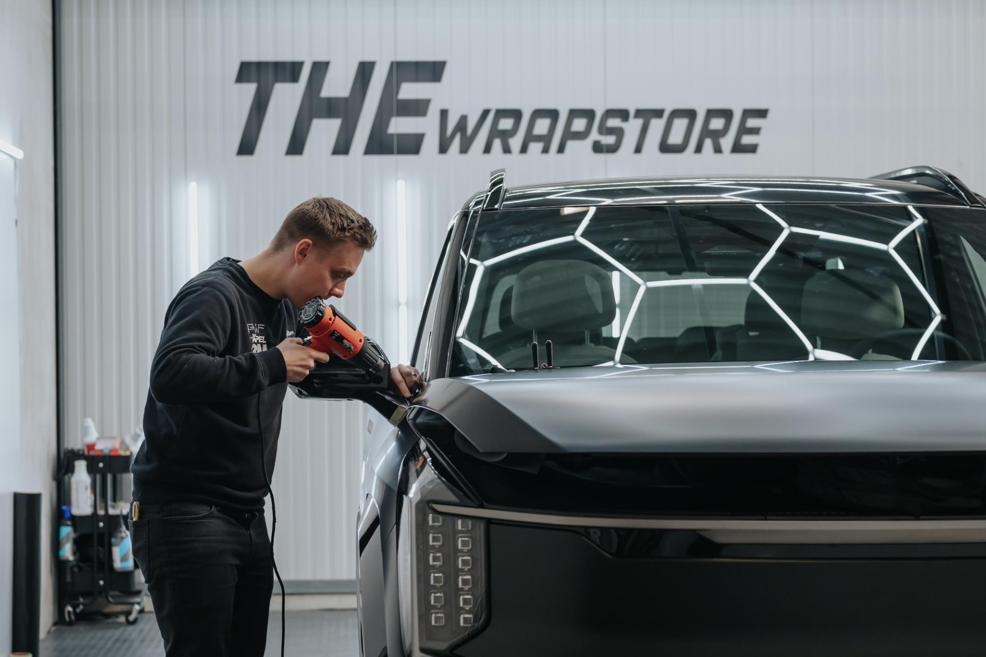 monteur brengt matte zwarte wrap aan op Kia EV9 voorkant met heatgun